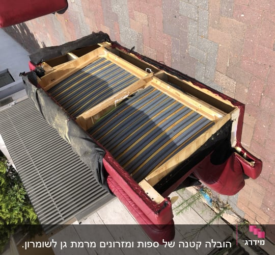 ספה הפוכה על מדרכה, חלקי עץ ופסי בד חשופים